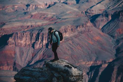 people man standing on rock cliff overlooking canyon during daytime nature