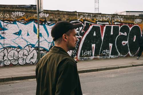 people man walking on asphalt road near wall with graffitis human
