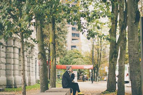 people person wearing black jacket and gray bonnet sitting on a chair human