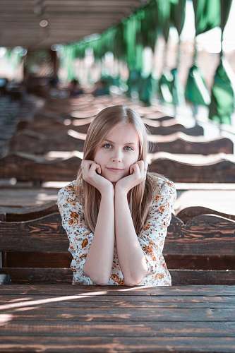 people selective focus of woman resting hands on face while sitting girl