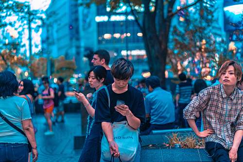 people selective focus photography of man sitting on concrete chair while holding smartphone human