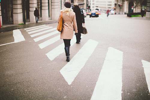 human two people walking on pedestrian lane towards gray concrete pillars during daytime photo people