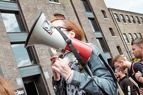 people woman holding red and white megaphone standing near building human