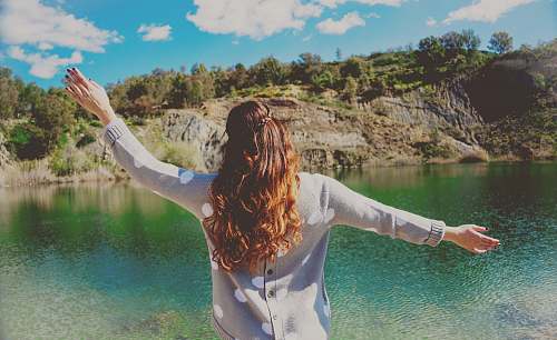 people woman in gray top standing near body of water woman