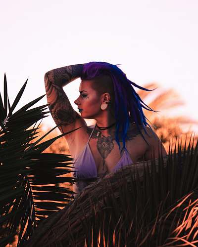 human woman in purple bikini top standing near plant while holding her head people