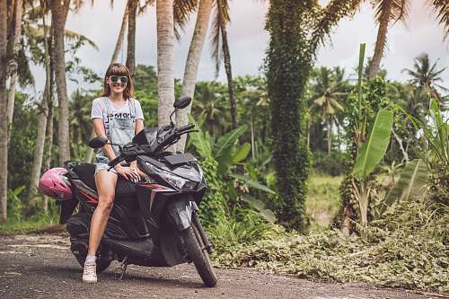 people woman smiling on top of black motor scooter human