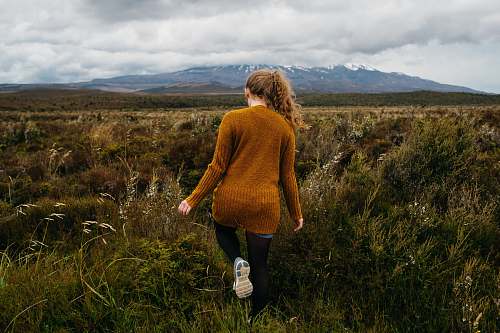people woman walking in grass field under stratocomulus clouds human