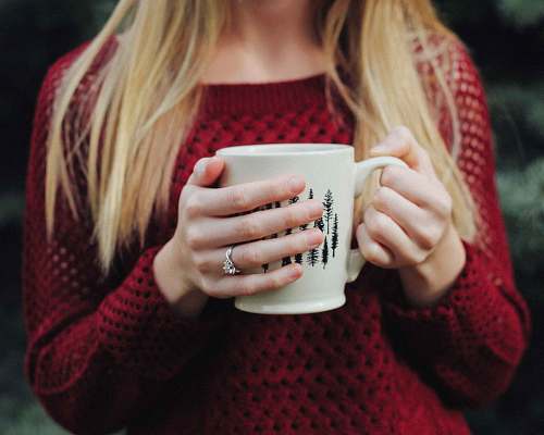 people woman wearing red sweater holding white and black ceramic mug human
