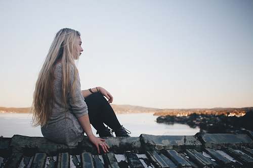 female woman sitting on gray dock near bpdy of water girl