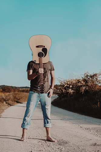 denim man holding brown acoustic guitar jeans