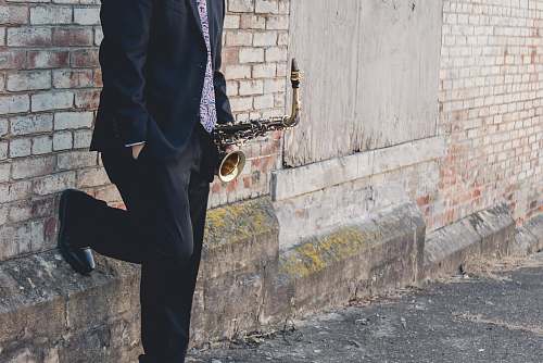 clothing man leaning on bricked wall shoe