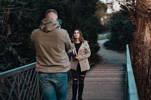 clothing man taking photo of woman on bridge coat