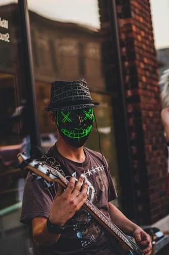 clothing person wearing black mask playing guitar hat