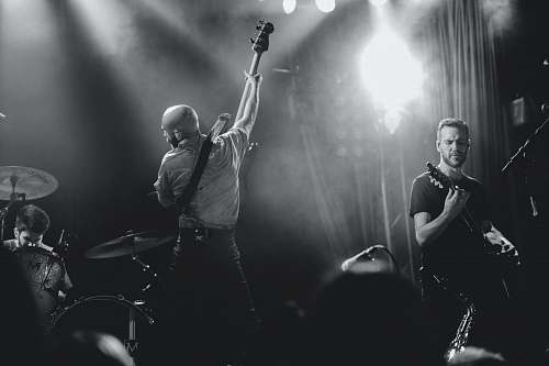 person grayscale photo of band playing on stage people