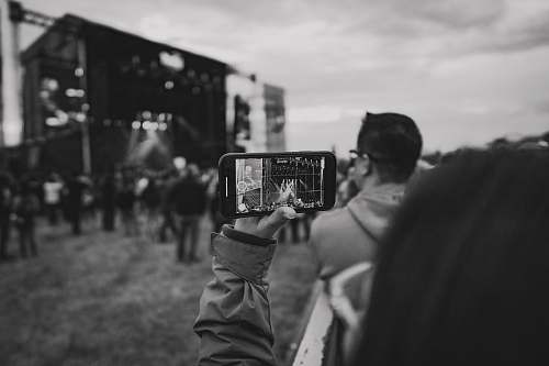 human grayscale photo of person holding smartphone person