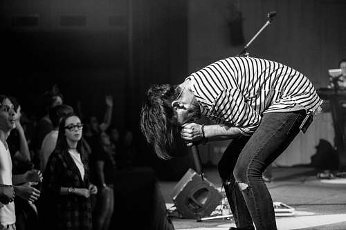 human grayscale photography of people watching a man performing on stage person