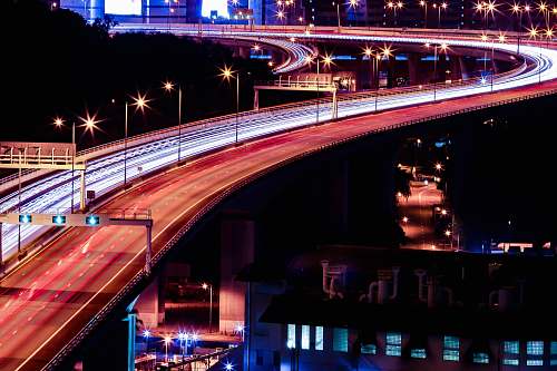 building time lapse photography of road with cars near building at night stage