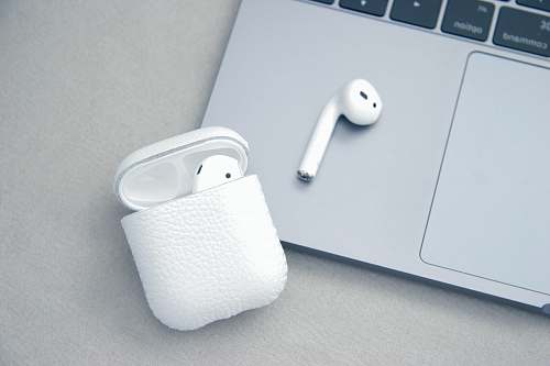 macbook white Apple AirPods beside MacBook Pro earphone