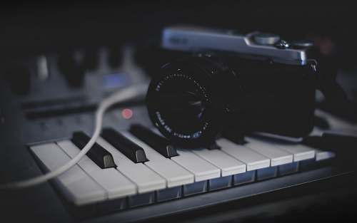 electronics black and gray SLR camera on keyboard camera