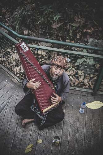 bandung man holding musical instrument sitting on the floor indonesia