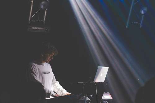 human man in white sweater playing electronic keyboard person