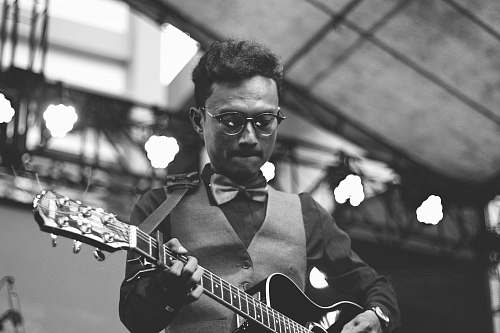 black-and-white greyscale photo of man playing guitar musical instrument
