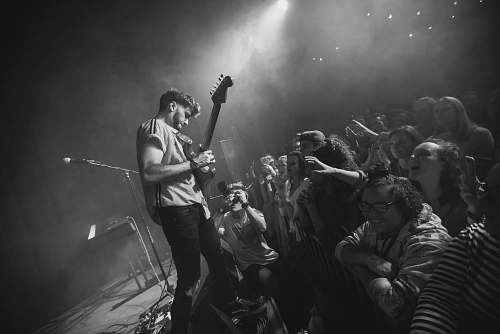 black-and-white man playing guitar facing fans human