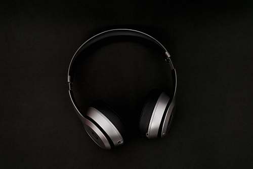 black-and-white silver headphones on top of black surface black