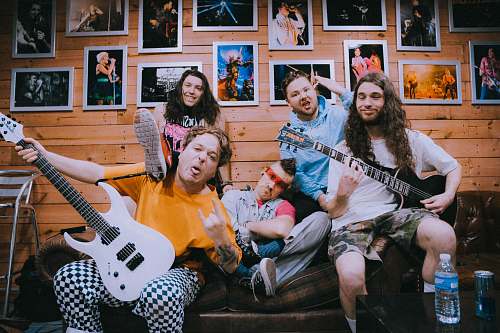 person band taking groufie picture on brown sofa people