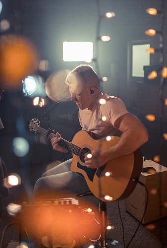 person bokeh photography of man playing guitar people