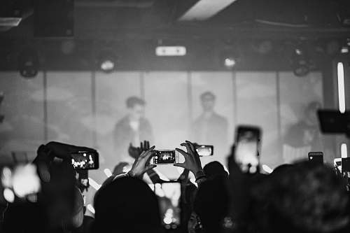 person crowd taking photo of man wearing black sunglasses black-and-white