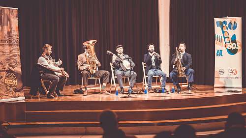 person five men playing instruments on stage people