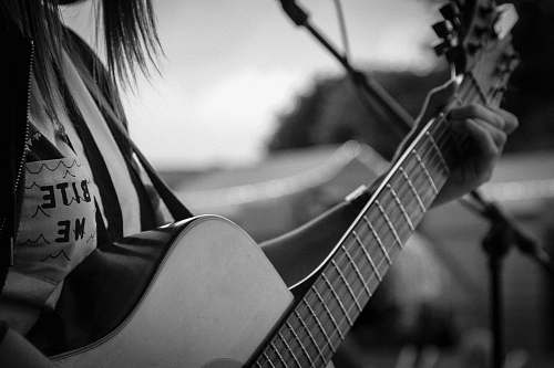 person grayscale and selective focus photography of woman playing guitar black-and-white
