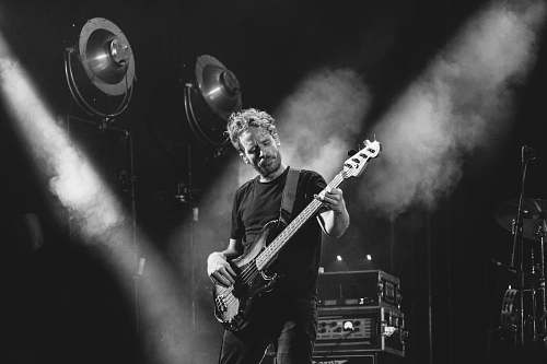 person grayscale photo of man playing bass guitar black-and-white
