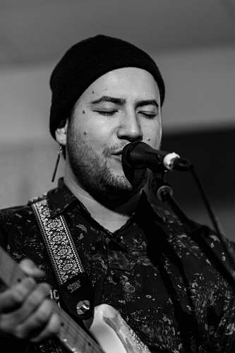 person grayscale photo of man playing guitar black-and-white