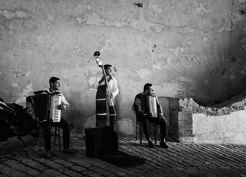 person grayscale photography of three men playing musical instruments black-and-white