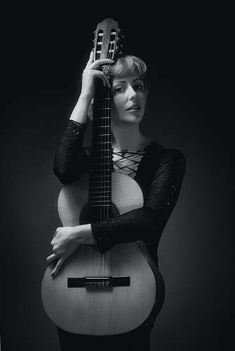 person grayscale photography of woman holding guitar black-and-white