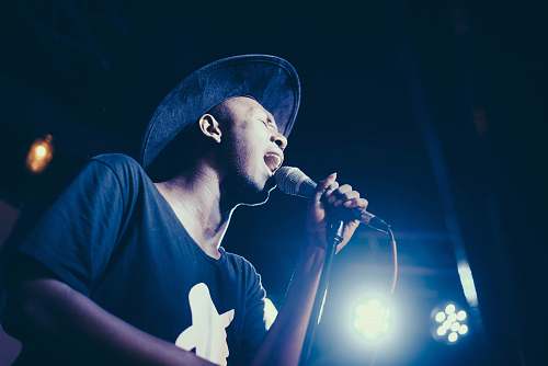 person low angle of man wearing cap singing in microphone people