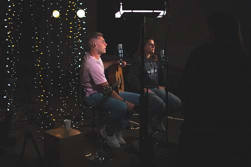 people man and woman sitting side by side in front of microphones person