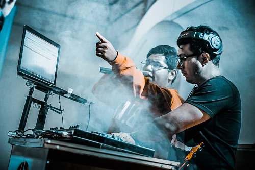 person man controlling DJ controller beside man with microphone people