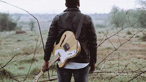 person man holding brown guitar people