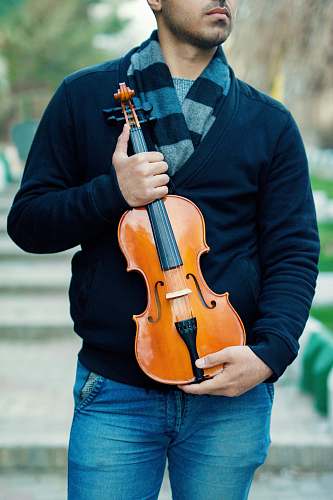 person man holding brown violin violin