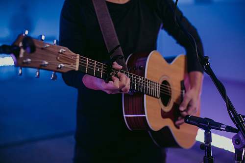 guitar man in black long sleeve shirt playing brown acoustic guitar musical instrument