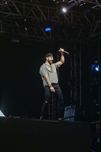 person man in gray t-shirt standing on stage lighting