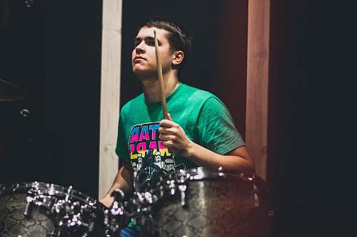 person man in teal crew neck t-shirt playing drum apparel