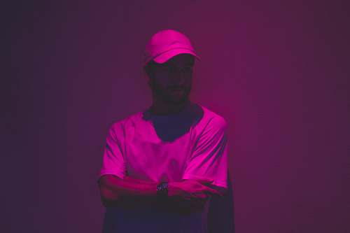 person man leaning of wall with purple light in fashion photography people
