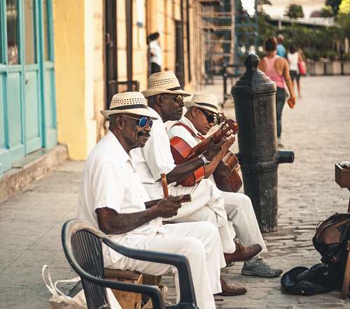 person man playing acoustic guitar while sitting on bench cuba