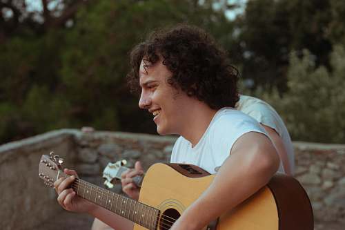 people man playing acoustic guitar while smiling person
