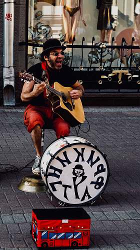 person man playing guitar in front of snare drum guitar