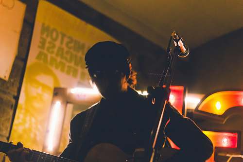 person man playing guitar near corded microphone people